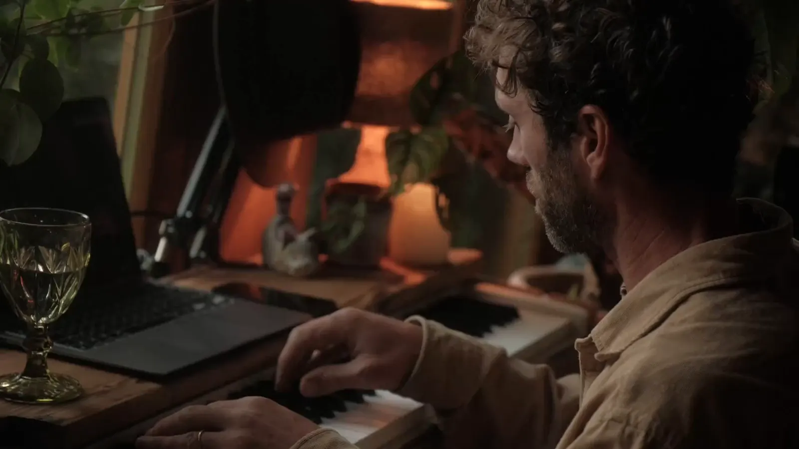 Boris Martel playing the piano in the evening light, among plants