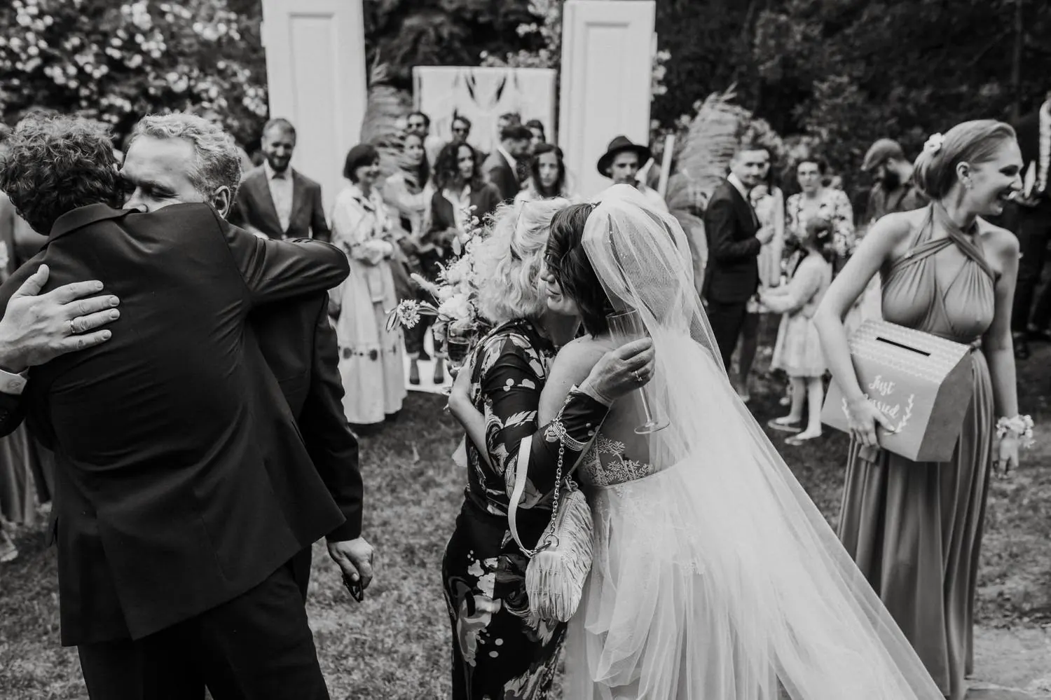 Guests embracing in a garden after the ceremony, black and white